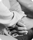 Close-up of two people holding hands in a gesture of support and compassion, symbolizing unity, comfort, and resilience in times of hardship.